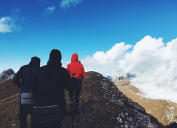 Rear view of people on mountain against blue sky