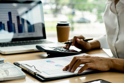 Midsection of woman using laptop on table