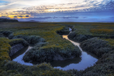 Scenic view of river against sky at sunset
