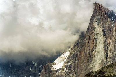 Low angle view of snow covered mountain against cloudy sky