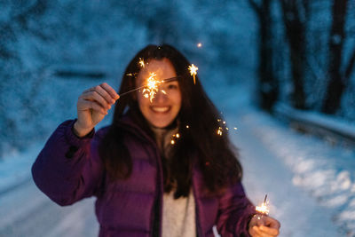 Woman lighting sparkles during winter while on a road trip in the mountains.