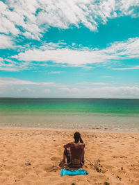 Rear view of man sitting on beach