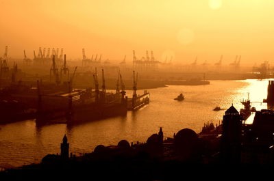 Silhouette boats in sea against sky during sunset