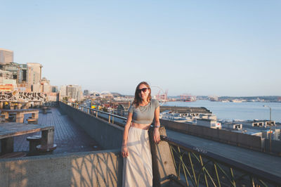 Woman standing by railing against sky