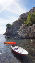 Boat on rock by sea against sky