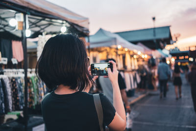 Rear view of woman photographing in city