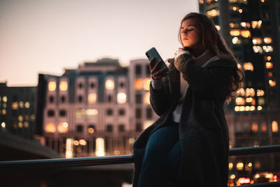 Young woman using mobile phone in city at night