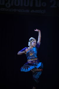 Rear view of woman standing against black background