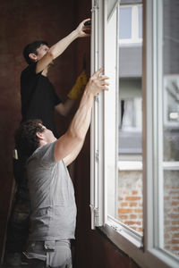 Young people install a window frame.