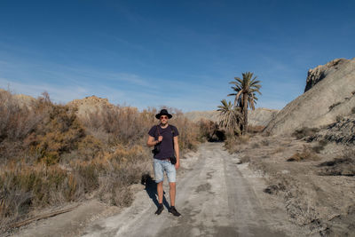 Full length portrait of man standing on road against sky