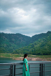 Rear view of woman standing against lake