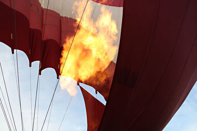 Low angle view of fire burning in hot air balloon against sky