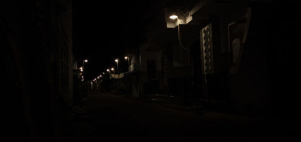 Illuminated street amidst buildings at night