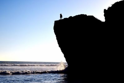 Silhouette woman on rock formation at beach