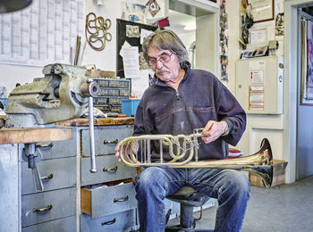 Instrument maker repairing trumpet in workshop