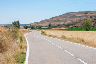 A empty road with curves crossing fields of crops