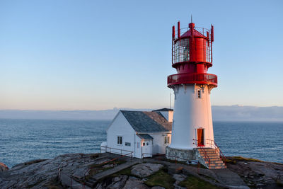 Lighthouse by sea against sky