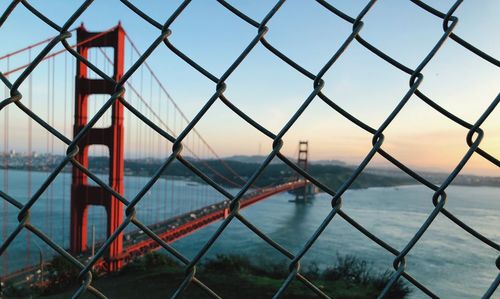 Close-up of chainlink fence against cloudy sky