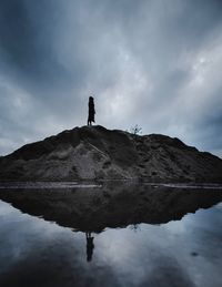 Silhouette man standing on mountain against sky