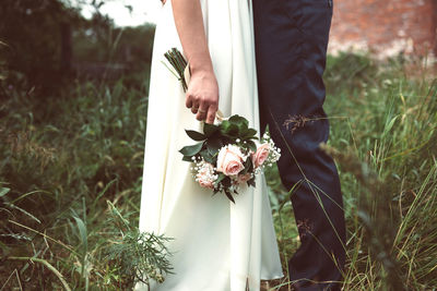 View of people standing by flowering plants on field