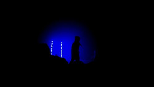 Silhouette man standing against illuminated blue lights