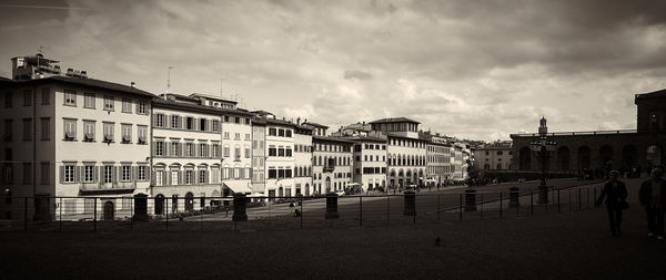 Buildings in city against cloudy sky