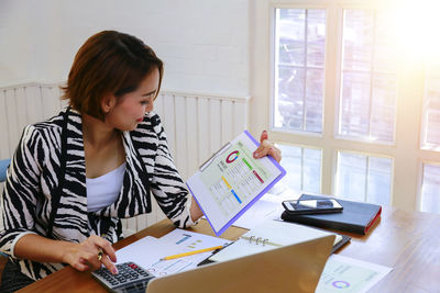 Woman using phone while sitting on table at home