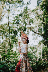 Woman standing by tree against plants