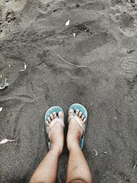 Low section of woman standing on sand