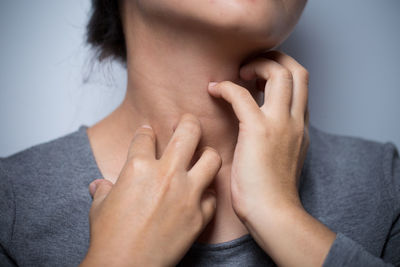 Midsection of woman with neckache against gray background