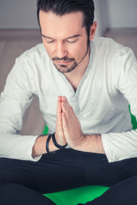 Mid adult man praying while sitting at home