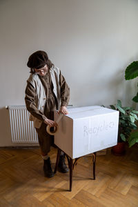 Eco responsible teen girl sealing with tape cardboard box with recyclable waste for recycling, reuse