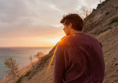 Side view of man standing on mountain against sky during sunset