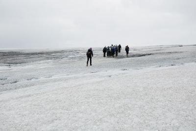 People walking on beach against sky