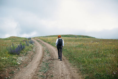 Rear view of woman walking on dirt road