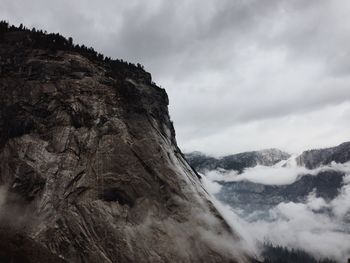 Scenic view of rocky mountains against cloudy sky in foggy weather at yosemite national park