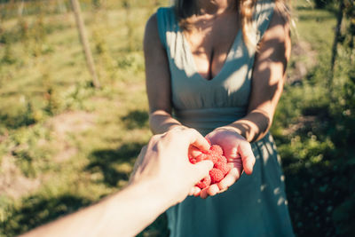 Midsection of woman holding hands on field