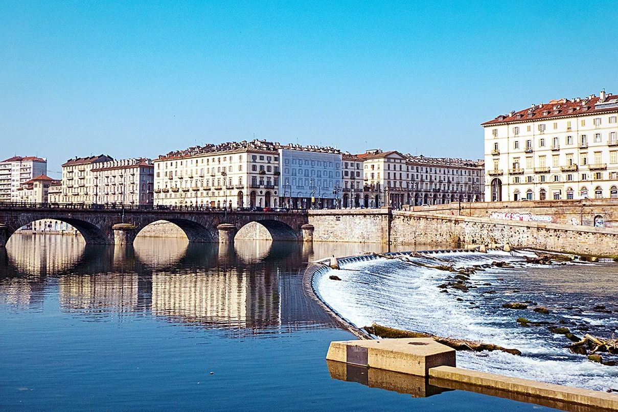 architecture, built structure, water, bridge, river, reflection, sky, building exterior, clear sky, nature, city, travel destinations, cityscape, transportation, blue, no people, travel, building, day, arch, sunny, waterway, waterfront, tourism, landmark, outdoors, arch bridge, history