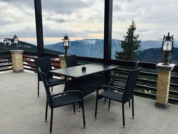 Empty chairs and tables in restaurant against sky