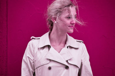 Close-up of young woman standing by red wall