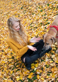 Woman with dog sitting on autumn leaves