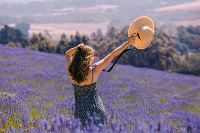 Woman holding her straw hat, standing in a lavender field. summertime
