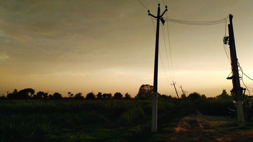 Silhouette trees on field against sky during sunset