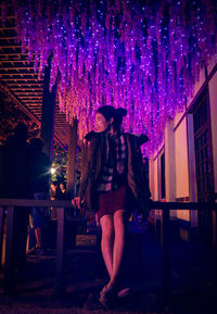 Full length of woman standing against illuminated building at night
