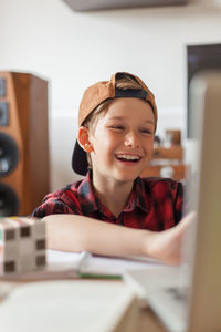 Happy elementary student talking to someone over video call at home.