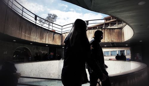 People standing by railing in city against sky