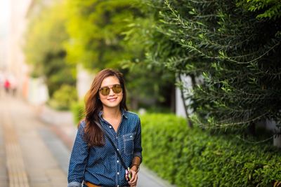 Portrait of smiling young woman wearing sunglasses standing outdoors