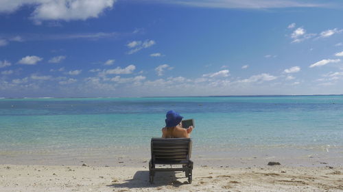 Rear view of woman sitting on beach