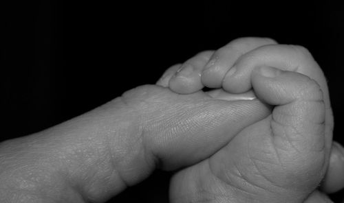 Cropped image of man holding hands against black background