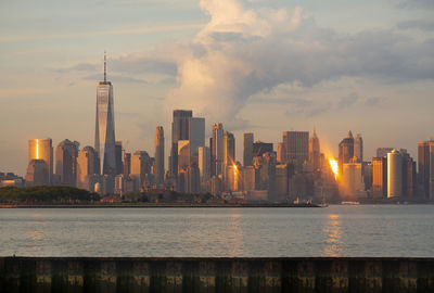 Sea by modern buildings against sky in city